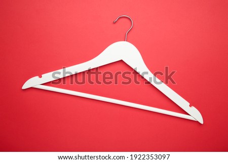 One wooden white hanger on red background. Store concept, empty hanger.