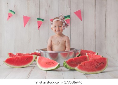 Ein Jahr altes Mädchen nimmt ein Bad mit Wassermelone. Papierfahne auf dem Hintergrund. 