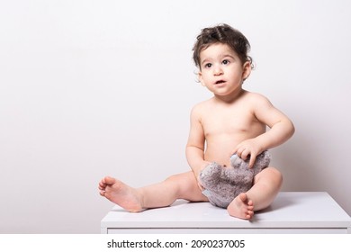 One Year Old Baby Wearing A Diaper And Playing With A Doll On A White Table