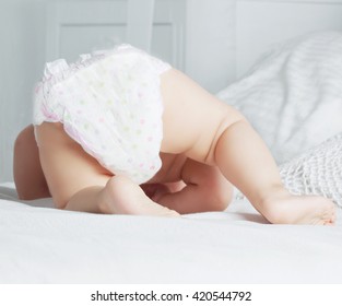 One Year Old Baby Wearing Diapers In Bed At Home 