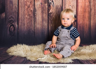 One year old blond baby sitting in front of wooden background in studio. Child studio photoshot with copy space
