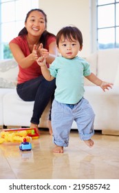 One Year Old Boy Taking First Steps With Mother