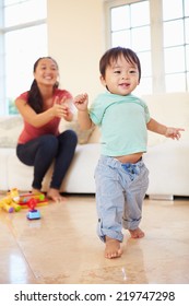 One Year Old Boy Taking First Steps With Mother