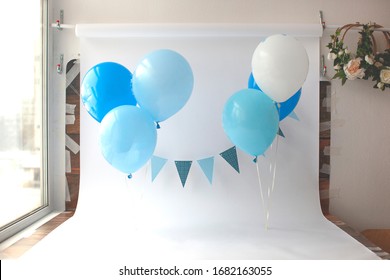 Ein Jahr altes Mädchen oder Junge machen ein Foto, Hintergrund für Fotografen, Feriendekor, DJ-Idee. Schmeißt Kuchen.Geburtstag. Hintergrund mit Ballon und Fahnen in blauen Farben. 