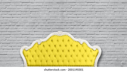 One yellow leather capitone chesterfield sofa headboard on background of gray painted brick wall with copy space, low angle, front view