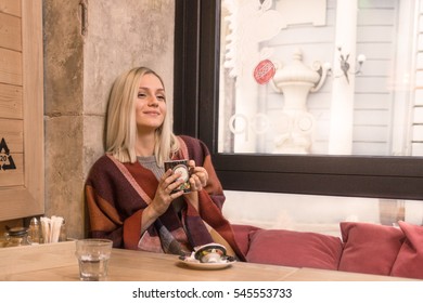 One Young Adult Woman  Enjoying Drinking Warm Blanket Tea Indoors Table. Winter Windows Street.