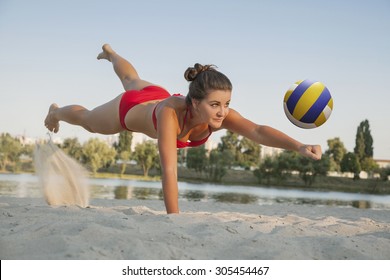 one young beautiful lady is playing volleyball on the beach, professional fly, summer time on beach. sport activity with red bikini making a save.