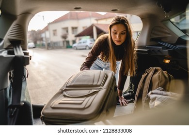 One young beautiful woman student travel concept female take luggage baggage suitcase and other stuff and belongings from the back of her car while moving into dormitory on college campus real people - Shutterstock ID 2128833008