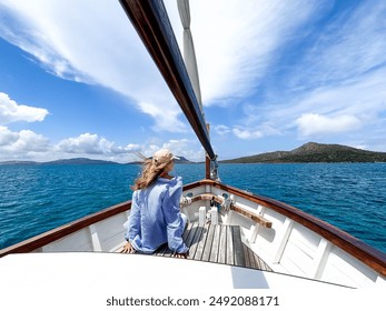 One young blonde woman sailing in a wooden boat in the middle of the ocean relaxing and enjoying sunny day of summer. Girl traveling lifestyle in tropical coastline - Powered by Shutterstock