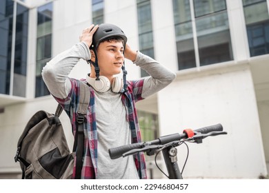 Un joven caucásico hombre adolescente generación Z con patada eléctrica patada scooter en el edificio moderno en la ciudad eco modo de transporte espacio de copia concepto