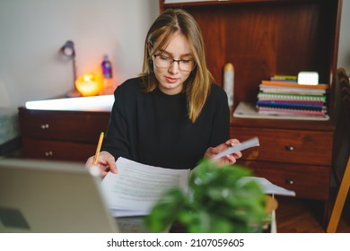 One young caucasian woman female student sitting at home writing and reading in her notebook holding pencil while study preparing for exam learning and education concept real people copy space