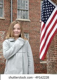 one young cute child with hand on her heart near an American Flag outdoors