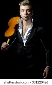 One Young Handsome Sensual Unshaven Bearded Man Looking At Camera With Popped Unbutton Collar White Shirt Black Jacket Keeping Violin Stays Forward In Studio On Black Background, Vertical Picture