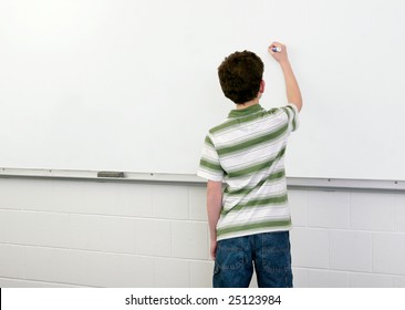 One Young Male Student In A Classroom Writing On A Whiteboard