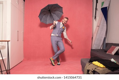 One Young Man, 20-29 Years Old, Posing With An Open Umbrella Inside A Studio. Shot In A Studio, Pink Background.