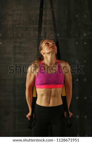 Similar – One young middle age athletic woman at crossfit training, exercising with trx suspension fitness straps over dark background, front view, looking up