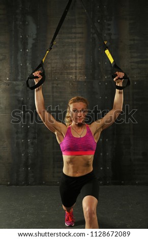 Similar – One young athletic woman at crossfit training, exercising with trx suspension fitness straps over dark background, front view, looking at camera