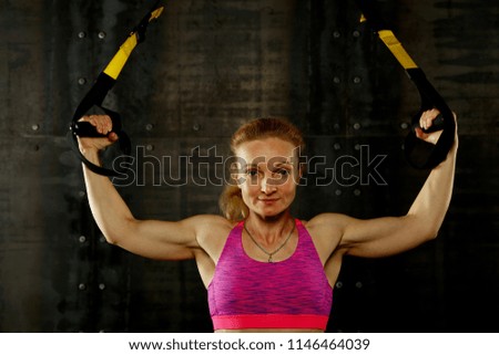 Similar – One young athletic woman at crossfit training, exercising with trx suspension fitness straps over dark background, front view, looking at camera