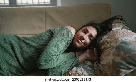 One young Middle Eastern woman laying on couch resting and relaxing. An Arab adult girl feeling unwinding