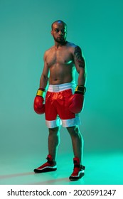 One Young Professional Male Boxer Standing And Looking Away Isolated On Blue Green Background In Neon Light. Full Length. Healthy Lifestyle, Sport And Motion Concept. Copy Space For Ad.