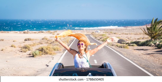 One Young Woman Enjoying And Having Fun In Their Vacations Outdoors - Female Person In Freedom Concept And Lifestyle With A Car In The Middle Of The Road Woth The Ocean Or Sea At The Background