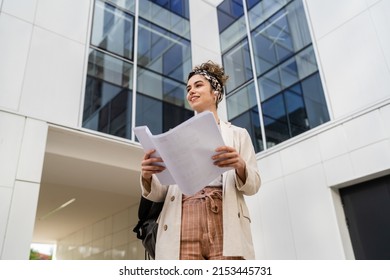 One Young Woman Female Businessman Or Student Checking Documents In Front Of Modern Building At University Or Company In Bright Day Real People Copy Space Standing Alone Hold Paper Happy Smile