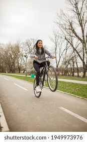 One Young Woman, Riding Bicycle Wheelie Style.