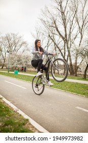 One Young Woman, Riding Bicycle Wheelie Style.