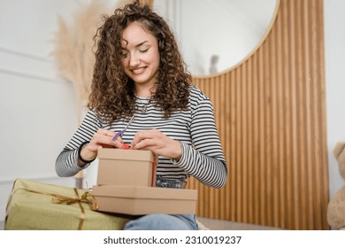 one young woman wrap presents at home happy female smile while holding wrapping paper ans gift box prepare to pack gifts for holiday season happy smile copy space real people - Powered by Shutterstock