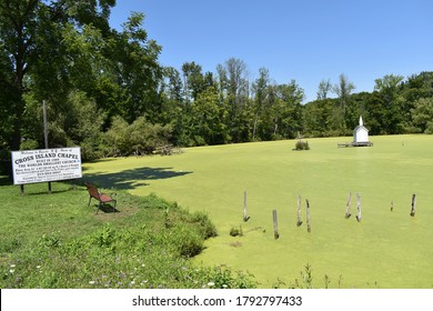 Oneida, New York, USA - August 9, 2020: Cross Island Chapel, the world's smallest church built in 1989, standing in the middle of a pond covered with green scum