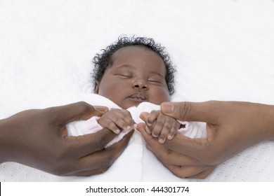 One-month-old baby girl sleeping next to her parents 
