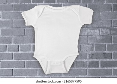 Onesie Photographed Against An Industrial Gray Brick Background.