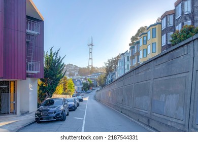 One-way Street In The Neighborhood In San Francisco, California With Road Parking Space. There Are Parked Cars On The Left Near The House Across The Concrete Wall Near The Row Of Apartment Buildings.