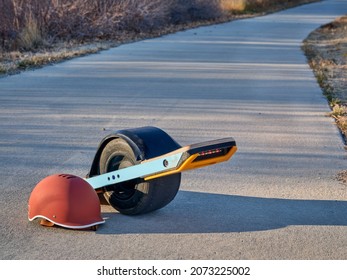 One-wheeled Electric Skateboard (personal Transporter) With A Helmet On A Paved Bike Trail