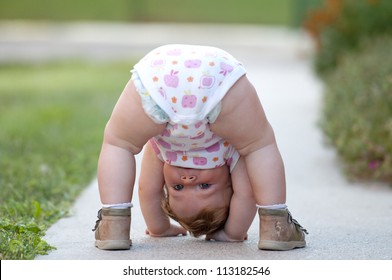 One-year baby girl playing upside down on the street - Shutterstock ID 113182546