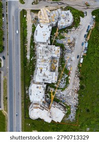 An ongoing construction project shows the floor plans and structure of a future building. Workers and machinery are present, with materials scattered around the site.