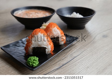 Onigiri or japanese rice balls served on the wooden tabletop in the restoran. Rice triangle with fish caviar and  seaweed. Japanese onigiri sushi. Korean Samgak-gimbap. Selective focus