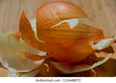Onion peel on a wooden cutting board glows in the bright light.