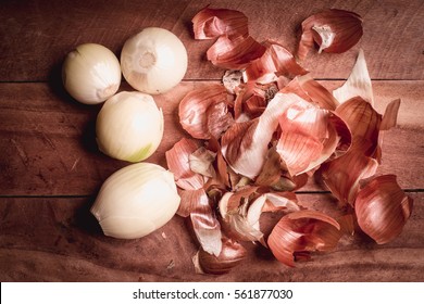 Onion peeled and skin on wooden background.