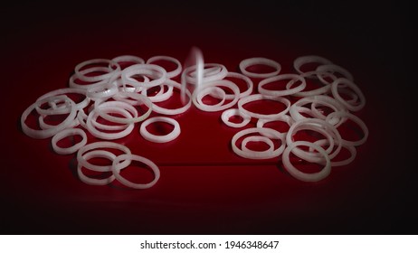 Onion Rings Falling On Table. Close Up View Of Falling White Sliced Ring Onion On Red Surface. Someone Throwing Onion Pieces On Table In Slow Motion. Cooking Process. 