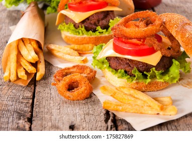 Onion rings,french fries and cheeseburger on the wooden table - Powered by Shutterstock