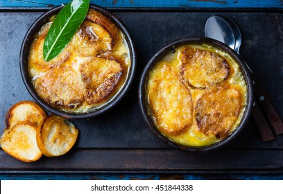 Onion Soup With Dried Bread And Cheese On Clay Bowls On Black Background. Top View