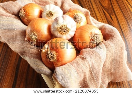 Onions and garlics. Garlic bulbs and onions in the wooden box.