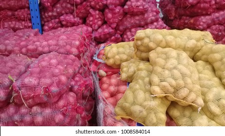 Onions and potatoes in stored in netting for distribution to market. - Shutterstock ID 1008584014