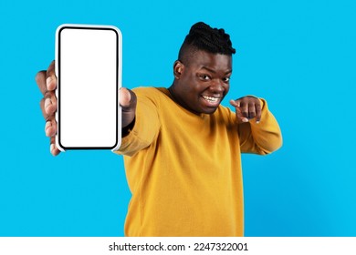 Online Ad. Smiling Black Male Pointing At Blank Smartphone In His Hand While Standing Isolated Over Blue Studio Background, Happy African American Man Recommending New App Or Website, Collage, Mockup - Shutterstock ID 2247322001