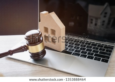 Online Auction for Real Estate concept. Judge gavel and house model on Notebook computer. Ideas for housing business judgment by E-commerce online goods services digital technology held over internet