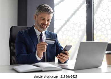 Online Banking. Middle Aged Businessman Using Smartphone And Credit Card In Office, Mature Male Entrepreneur In Suit Making Money Transfers Or Shopping In Internet, Enjoying E-Commerce, Copy Space - Powered by Shutterstock