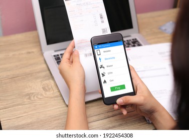 Online Bill Payment Concept.Hands Holding Mobile Phone On Blurred Electric Bill As Background