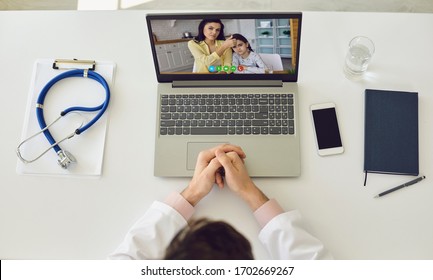 Online Call Pediatrician. Doctor Online. Therapist Consults A Family Mother And Her Daughter Using A Laptop Sitting At Home. Top View.