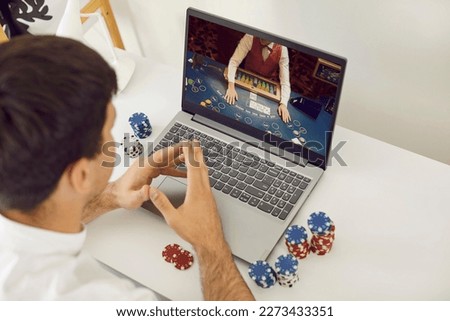Online casino. Young smart male online poker player relaxing gambling on his laptop computer at home. Concept of online gambling, win money, sports bet, chance, succeed, fortune and addiction.